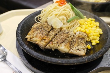 Japanese cuisine, cooked noodles with grilled chickens in steel hot plate served with sweet corn