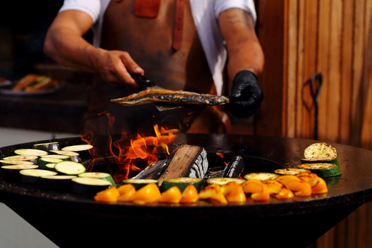 повар на улице готовит овощи гриль с рыбой