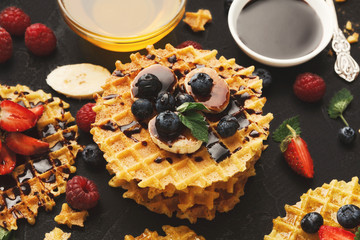 Waffles with berries and fruits, breakfast at black background