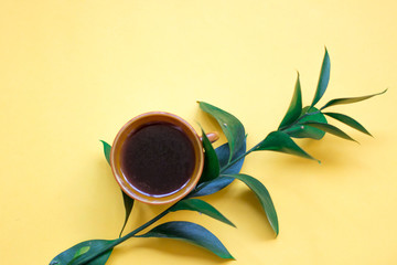 minimalist Flat lay, yellow background, Cup of coffee, green branch
