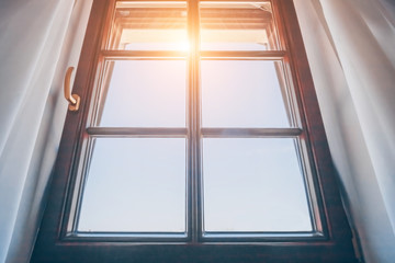 Bright morning sun in the open window through the curtains