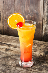 Tequila sunrise cocktail in glass on wooden table