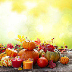 Fall harvest of pumpkins with leaves and candles on wooden table, copy space on fall garden background