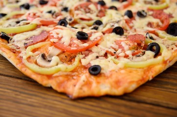 Preparation of homemade pizza with salami, mushrooms, olives, tomatoes and greens
