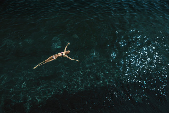 aerial view of a woman floating and reraxing in the sea