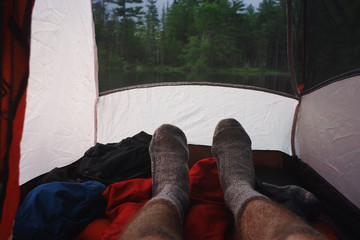 Man relaxing with Wool Socks while camping in a tent in the Adirondack mountains