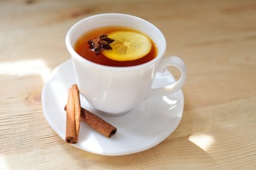 a cup of black tea with a lemon with cinnamon and a badan on a close-up table