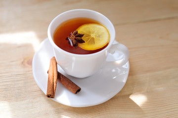 a cup of black tea with a lemon with cinnamon and a badan on a close-up table