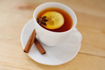 a cup of black tea with a lemon with cinnamon and a badan on a close-up table