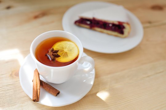 a cup of black tea with a lemon with cinnamon and a badan on a close-up table