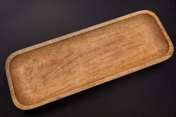 A long wooden plate on a dark background  