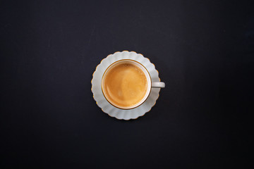 White porcelain cup of black coffee on a dark background. View from above. Symmetry.  