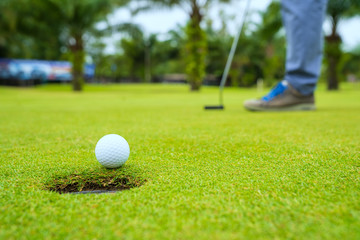 Golfer putting golf ball on the green golf, lens flare on sun set evening time, Pro Golf long putting golf ball in to the hole, sunset scene time.