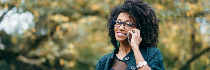 Happy black woman during a mobile phone call in autumn - 218808529