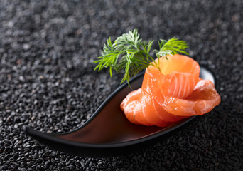 Salted salmon with dill on the background of black sesame.