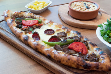 Turkish Mixed Pide with Minced Meat, Cheese, Sausage (Sucuk), Tomatoes and Red Pepper served with Salad and Pickles.