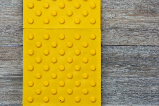 Top view of footpath tiles on a marble texture cover. Yellow circle buttons pattern. A stop signal for blind person.