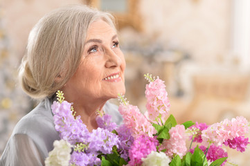 portrait of beautiful senior woman posing with flowers 