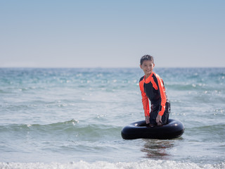 little Asian boy play waves on the beach , with a lifebuoy