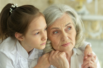 Portrait of a sad grandmother and granddaughter hugging