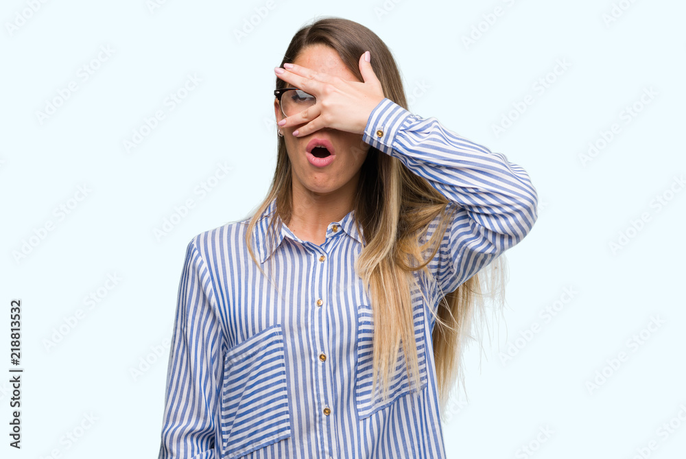 Canvas Prints Beautiful young woman wearing elegant shirt and glasses peeking in shock covering face and eyes with hand, looking through fingers with embarrassed expression.