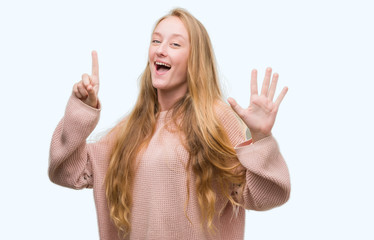 Blonde teenager woman wearing pink sweater showing and pointing up with fingers number six while smiling confident and happy.