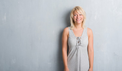 Adult caucasian woman over grunge grey wall wearing a dress with a happy face standing and smiling with a confident smile showing teeth