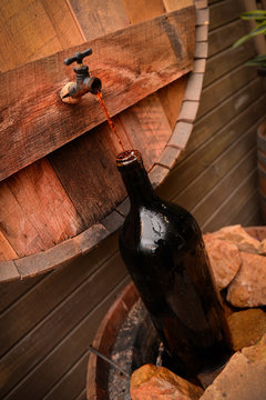 Corked barrel of wine pouring into a large wine bottle