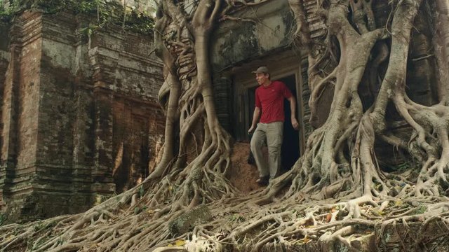 A photographer is exploring the root covered ancient Khmer temple of Prasat Bram in Cambodia's Preah Vihear province