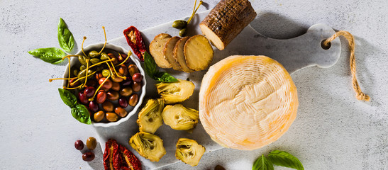 banner of several types of Italian cheese from Puglia and cold snacks on the table. Artichokes in...