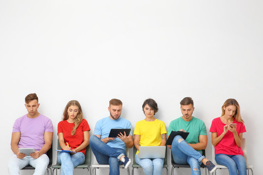 Group Of Young People Waiting For Job Interview Near Light Wall