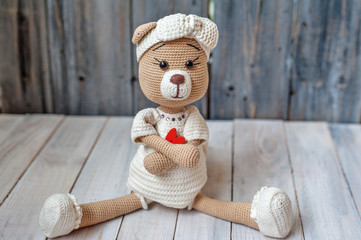 The knitted toy on a wooden table. Handmade. It can be used as a background