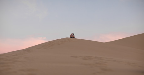 Fototapeta na wymiar guy and girl on a sand dune