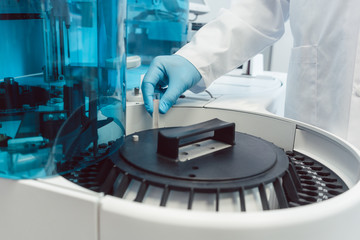 Labortechniker bestückt Zentrifuge mit Blutröhrchen