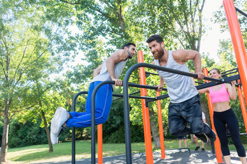 Two strong young men doing dips exercise for the upper body outdoors