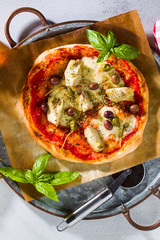 Classic Italian Pizza Margherita with artichokes, olives and capers on a table with beer and a knife. Banner for restaurants, advertising.