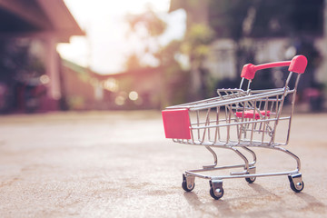 Shopping concept : Small red shopping cart toy on concrete floor. online shopping consumers can...