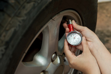 Tire pressure gauge : Hand holding pressure gauge checking air pressure for car tire. Safe driving.