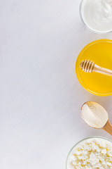 Dairy products and honey with wooden cutlery. Cottage cheese, sour cream, cream on a white background top view. Different natural products for vegan. Healthy food. Copy space