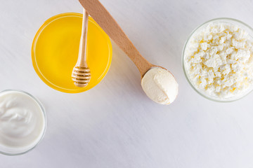 Dairy products and honey with wooden cutlery. Cottage cheese, sour cream, cream on a white background top view. Different natural products for vegan. Healthy food. Copy space