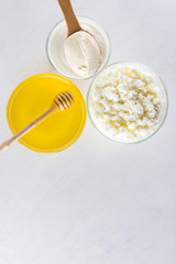 Dairy products and honey with wooden cutlery. Cottage cheese, sour cream, cream on a white background top view. Different natural products for vegan. Healthy food. Copy space