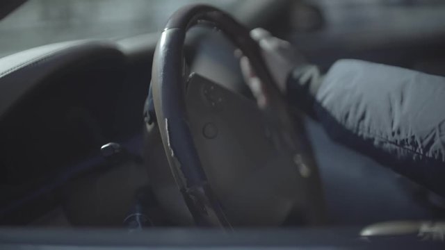 hand turns steering wheel in expensive car.