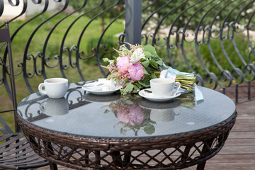 cups of coffee and a bouquet of peonies on a glass table