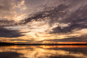 Sunset in the lake. beautiful sunset behind the clouds above the over lake landscape background. dramatic sky with cloud at sunset