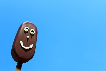 Stieleis mit Gesicht vor blauem Himmel