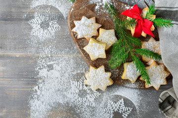 Preparation for new year 2019: pastry biscuits in the form of stars with powdered sugar, decorated  red bow and branches of a Christmas tree. the table with powdered sugar in the form of a snowflake