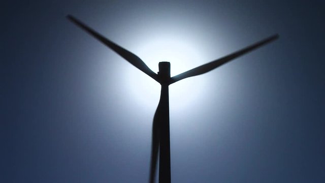 Zoom IN and OUT of a Wind turbine silhouette with sun in backlight. Unlimited renewable energy.