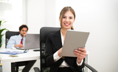 Smiling woman using a tablet in her office