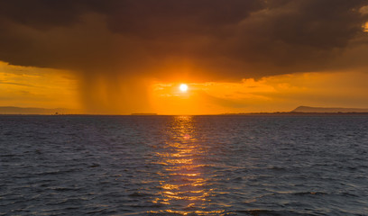 Sunset scene over the lake with rainy storm