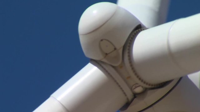 Nose Close Up Of Rotating Wind Turbine Blades In The Blue dark blue Sky in background. Unlimited renewable energy.